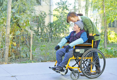 10月11日，張學(xué)琴用輪椅推著母親在校園里散步。