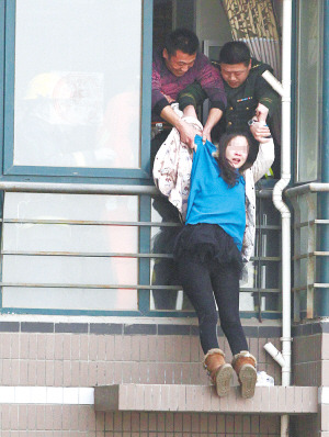 年輕女子在高樓窗外一小平臺坐了1個多小時后,被消防官兵拉進屋內。 年輕女子在高樓窗外一小平臺坐了1個多小時后,被消防官兵拉進屋內。