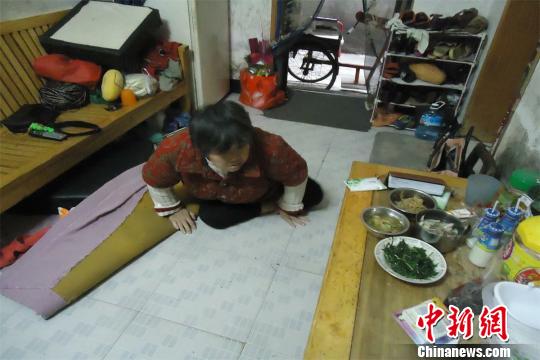 17日下午，56歲小兒麻痹癥患者張紅英爬在地板上找東西。 蘇路程 攝